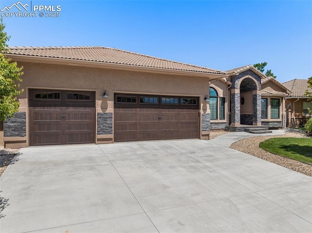 24 Redondo Ln, Pueblo, CO 81005 - mediterranean / spanish home featuring stone siding, a garage, concrete driveway, and a tiled roof