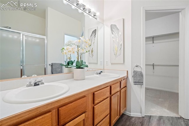 1020 Samuel Pt, Colorado Springs, CO 80906 - bathroom with double vanity, a stall shower, a walk in closet, and wood finished floors