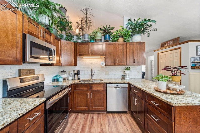 6150 Fall River Dr, Colorado Springs, CO 80918 - kitchen with stainless steel appliances, a sink, light wood finished floors, a peninsula, and tasteful backsplash