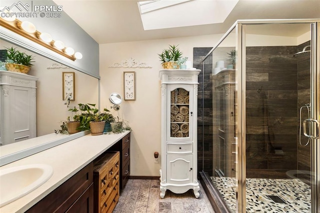 6150 Fall River Dr, Colorado Springs, CO 80918 - bathroom featuring a skylight, vanity, wood finished floors, a stall shower, and baseboards