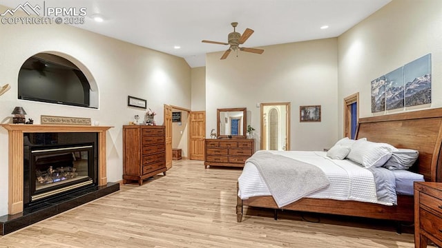17910 Queensmere Dr, Monument, CO 80132 - bedroom with wood finished floors, high vaulted ceiling, a glass covered fireplace, a ceiling fan, and recessed lighting
