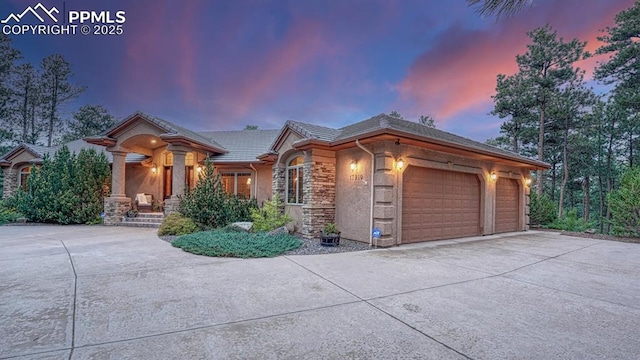 17910 Queensmere Dr, Monument, CO 80132 - view of front of house featuring driveway, a garage, stone siding, a tile roof, and stucco siding