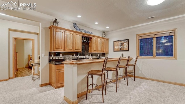 17910 Queensmere Dr, Monument, CO 80132 - kitchen featuring light carpet, a kitchen breakfast bar, decorative backsplash, recessed lighting, and baseboards