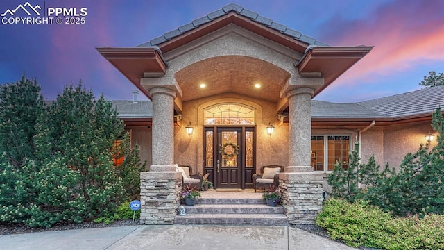17910 Queensmere Dr, Monument, CO 80132 - exterior entry at dusk featuring covered porch, stucco siding, and a tiled roof