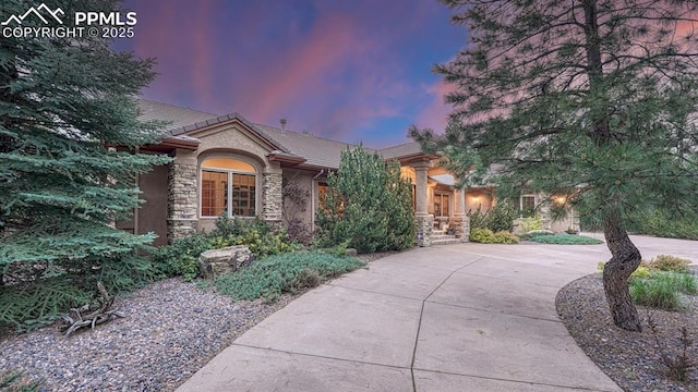 17910 Queensmere Dr, Monument, CO 80132 - view of front of house with stone siding, a tile roof, curved driveway, and stucco siding