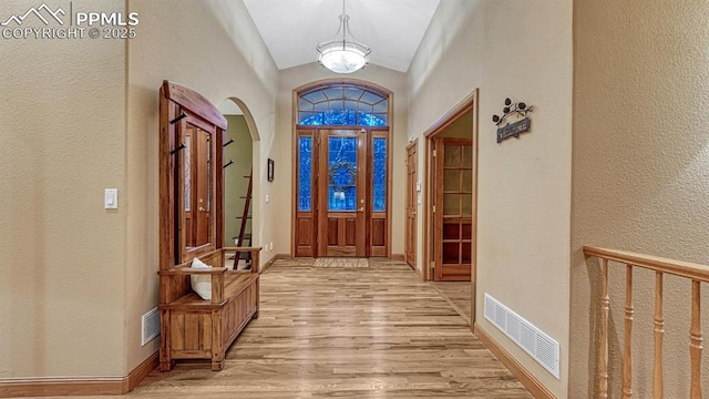 17910 Queensmere Dr, Monument, CO 80132 - entryway featuring arched walkways, light wood-style flooring, vaulted ceiling, a textured wall, and a chandelier