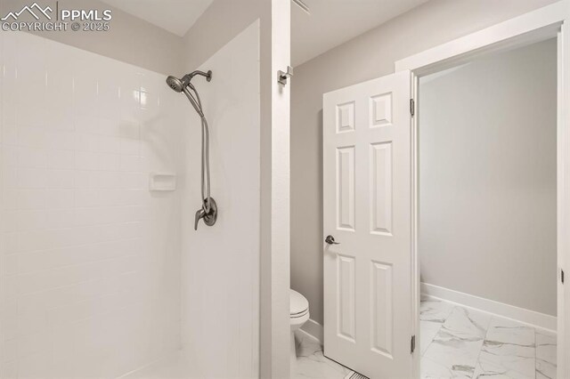 610 E San Gabriel Pl, Colorado Springs, CO 80906 - bathroom featuring marble look tiles, toilet, a tile shower, and baseboards
