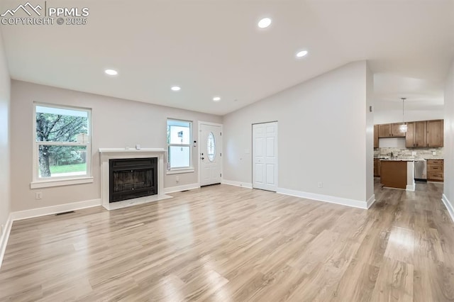 610 E San Gabriel Pl, Colorado Springs, CO 80906 - unfurnished living room featuring lofted ceiling, a fireplace with flush hearth, baseboards, light wood finished floors, and recessed lighting
