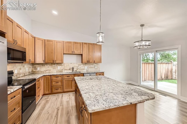 610 E San Gabriel Pl, Colorado Springs, CO 80906 - kitchen with stainless steel appliances, a sink, light wood-style flooring, tasteful backsplash, and a center island