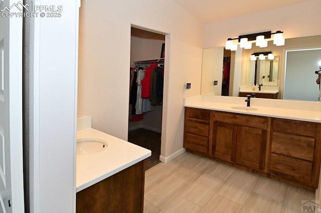 1213 E Tidy Dr, Pueblo, CO 81007 - bathroom featuring two vanities, a walk in closet, and baseboards