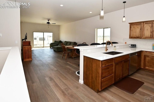 1213 E Tidy Dr, Pueblo, CO 81007 - kitchen with dishwasher, a sink, a peninsula, tasteful backsplash, and dark wood-style floors