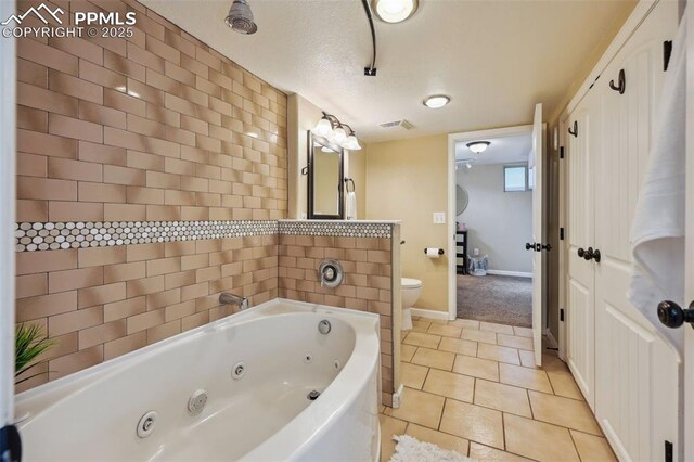 107 N Logan Ave, Colorado Springs, CO 80909 - bathroom with toilet, a tub with jets, tile patterned flooring, and baseboards