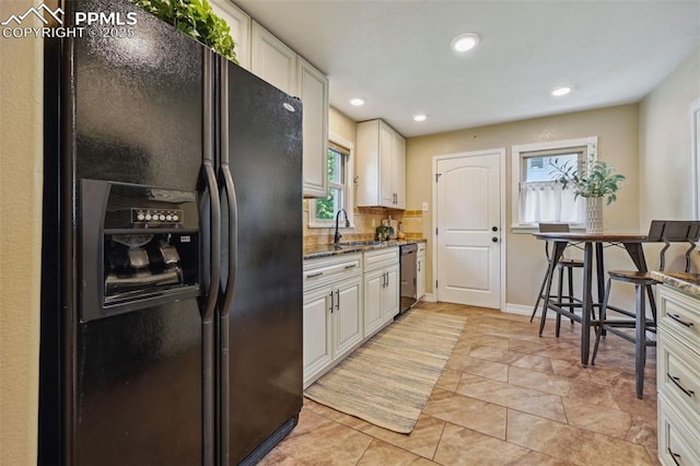 107 N Logan Ave, Colorado Springs, CO 80909 - kitchen featuring black refrigerator with ice dispenser, dishwasher, dark stone countertops, white cabinetry, and recessed lighting