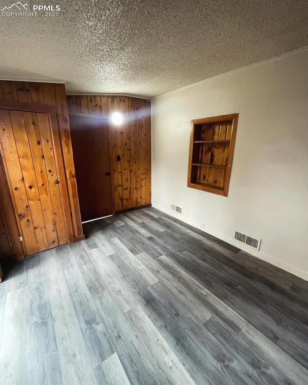 109 Cheyenne Blvd, Colorado Springs, CO 80905 - unfurnished bedroom featuring wood finished floors, a textured ceiling, baseboards, wood walls, and a closet