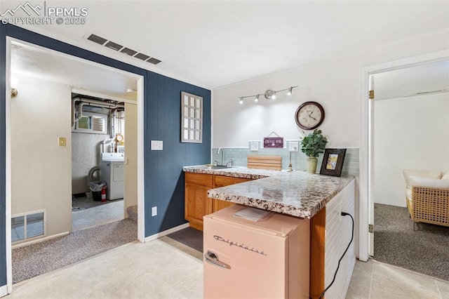 4534 Bella Dr, Colorado Springs, CO 80918 - kitchen featuring washer / clothes dryer, light countertops, a peninsula, brown cabinets, and light carpet