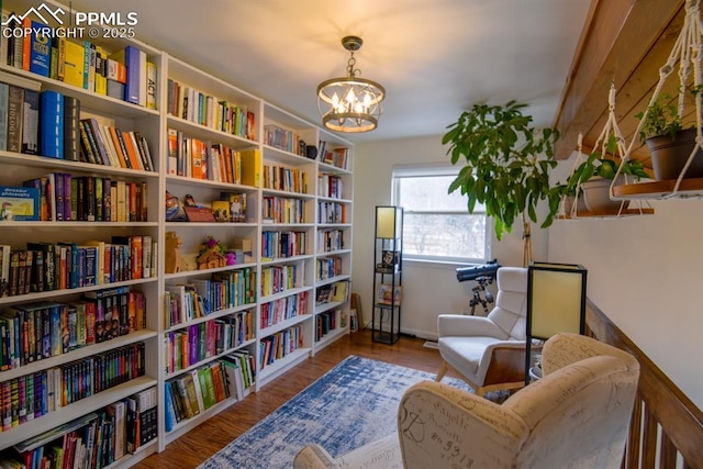 105 Pauma Valley Dr, Colorado Springs, CO 80921 - sitting room featuring bookshelves, a chandelier, baseboards, and wood finished floors