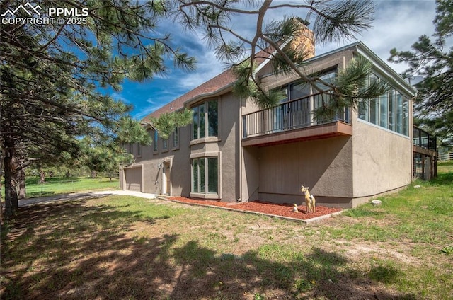 16070 Buggywhip Dr, Elbert, CO 80106 - back of house featuring a balcony, stucco siding, a sunroom, and a lawn