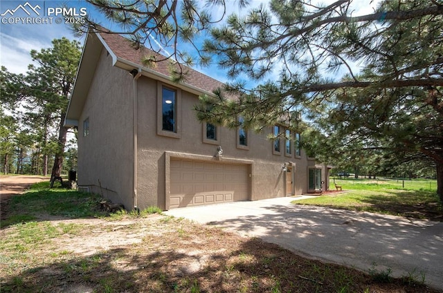 16070 Buggywhip Dr, Elbert, CO 80106 - view of side of property featuring an attached garage, stucco siding, and driveway