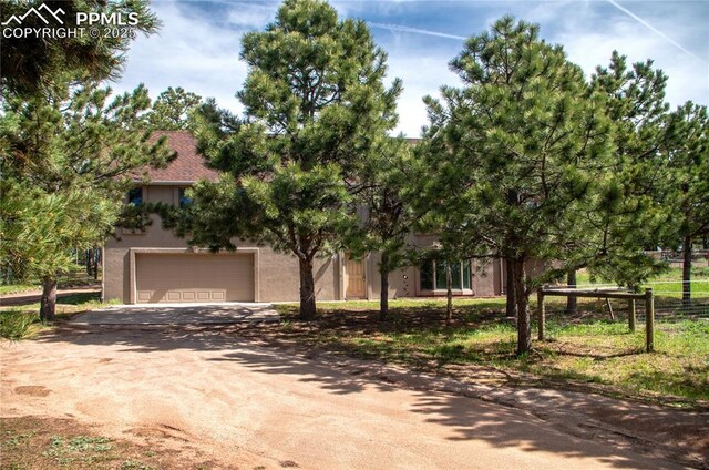 16070 Buggywhip Dr, Elbert, CO 80106 - obstructed view of property with stucco siding, dirt driveway, and an attached garage