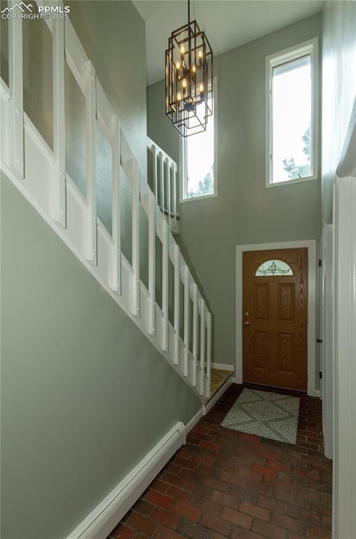 16070 Buggywhip Dr, Elbert, CO 80106 - foyer featuring brick floors, a towering ceiling, a chandelier, a baseboard radiator, and stairs