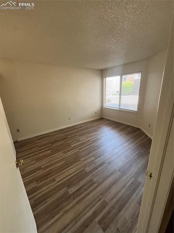 912 Acapulco Ct, Colorado Springs, CO 80910 - spare room with a textured ceiling, dark wood-type flooring, and baseboards