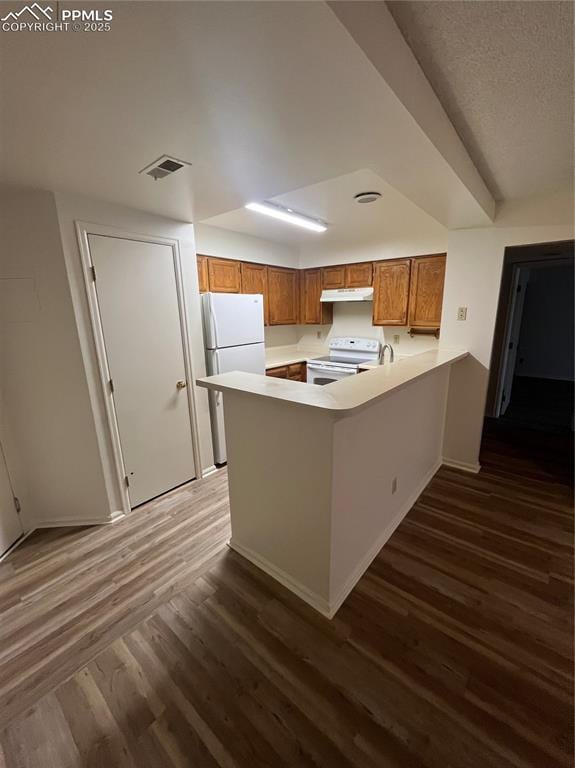 912 Acapulco Ct, Colorado Springs, CO 80910 - kitchen with white appliances, a peninsula, brown cabinetry, and dark wood finished floors