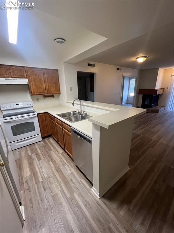 912 Acapulco Ct, Colorado Springs, CO 80910 - kitchen featuring electric range, dishwasher, under cabinet range hood, a sink, and brown cabinetry