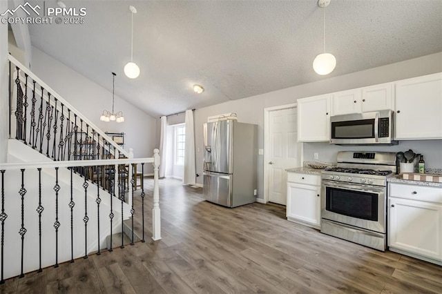13072 Westlake Pl, Broomfield, CO 80020 - kitchen featuring appliances with stainless steel finishes, white cabinetry, wood finished floors, lofted ceiling, and a textured ceiling
