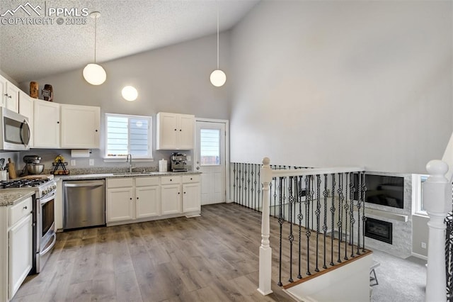 13072 Westlake Pl, Broomfield, CO 80020 - kitchen featuring stainless steel appliances, white cabinets, light stone countertops, a textured ceiling, and light wood-style flooring