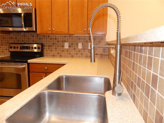 828 S Wahsatch Ave, Colorado Springs, CO 80903 - kitchen featuring stainless steel appliances, tasteful backsplash, a sink, and brown cabinetry