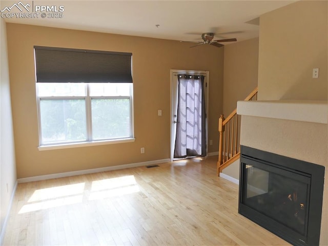 828 S Wahsatch Ave, Colorado Springs, CO 80903 - unfurnished living room with light wood-type flooring, stairway, a ceiling fan, and baseboards