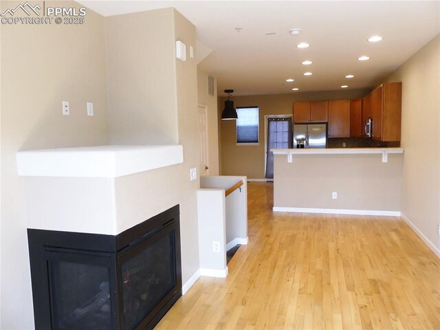 828 S Wahsatch Ave, Colorado Springs, CO 80903 - kitchen with appliances with stainless steel finishes, brown cabinets, a peninsula, light wood-type flooring, and baseboards