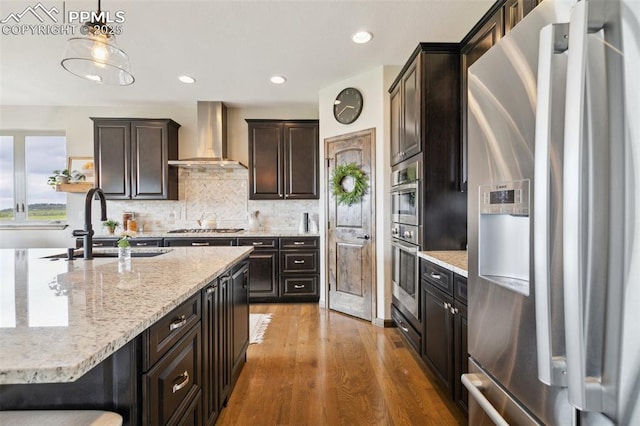 4808 Silver Nell Dr, Colorado Springs, CO 80908 - kitchen with appliances with stainless steel finishes, wall chimney range hood, a sink, wood finished floors, and decorative backsplash
