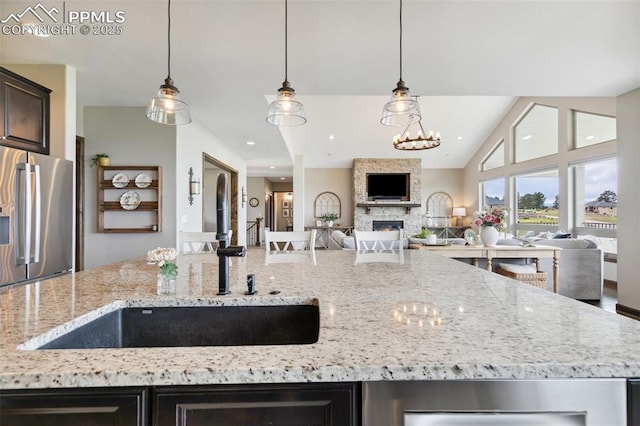 4808 Silver Nell Dr, Colorado Springs, CO 80908 - kitchen featuring stainless steel fridge with ice dispenser, a sink, open floor plan, a fireplace, and light stone counters