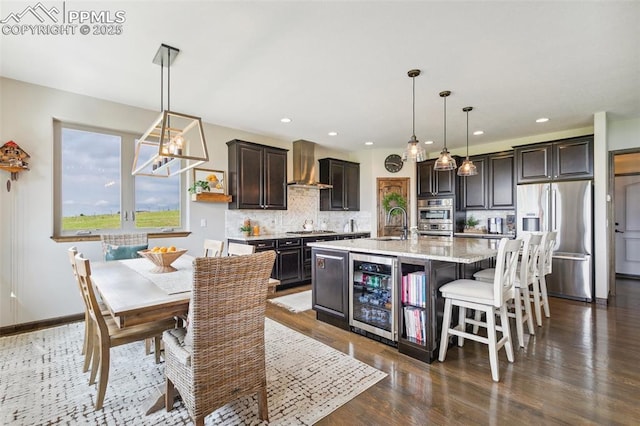 4808 Silver Nell Dr, Colorado Springs, CO 80908 - kitchen with stainless steel appliances, wine cooler, wall chimney exhaust hood, tasteful backsplash, and a center island with sink
