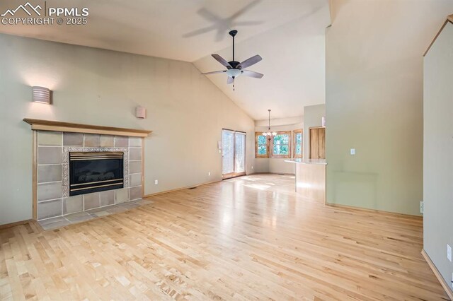 5437 Lions Gate Ln, Colorado Springs, CO 80919 - unfurnished living room with high vaulted ceiling, wood finished floors, a ceiling fan, a fireplace, and a chandelier