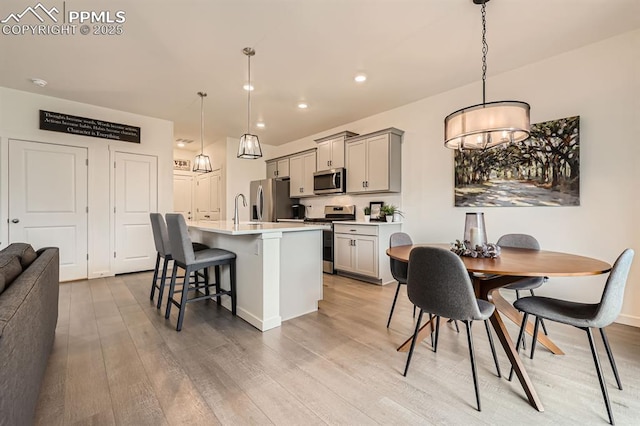 16135 Mountain Flax Dr, Monument, CO 80132 - kitchen featuring stainless steel appliances, gray cabinetry, a kitchen island with sink, light wood-style flooring, and recessed lighting