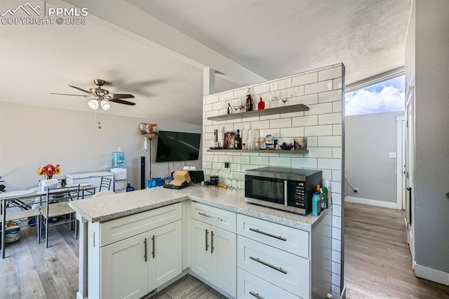 113 Ely St, Colorado Springs, CO 80911 - kitchen with open shelves, stainless steel microwave, light wood-type flooring, a ceiling fan, and a peninsula