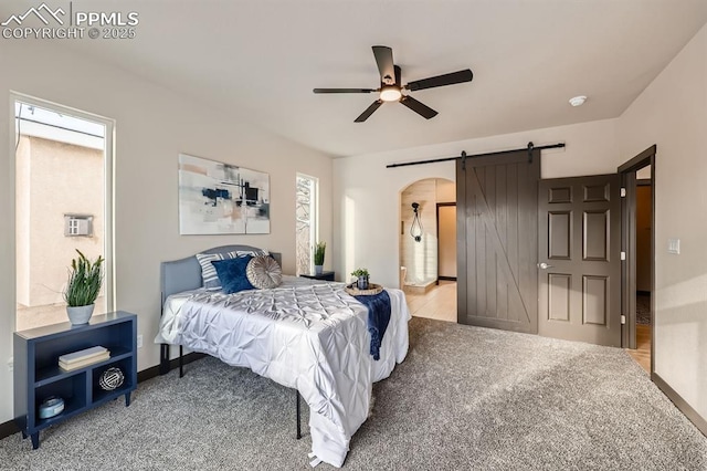 5687 Marshall Creek Dr, Colorado Springs, CO 80924 - bedroom with a barn door, carpet, baseboards, a ceiling fan, and arched walkways