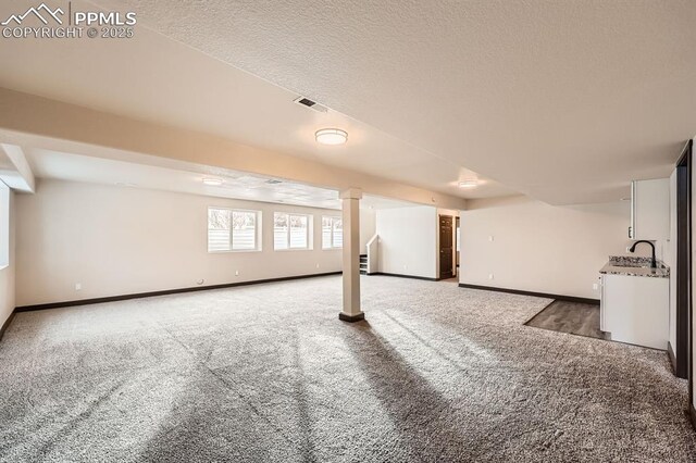 5687 Marshall Creek Dr, Colorado Springs, CO 80924 - basement with light colored carpet, baseboards, stairway, a sink, and a textured ceiling