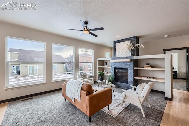 5687 Marshall Creek Dr, Colorado Springs, CO 80924 - carpeted living room with a fireplace, a ceiling fan, baseboards, a textured ceiling, and wood finished floors