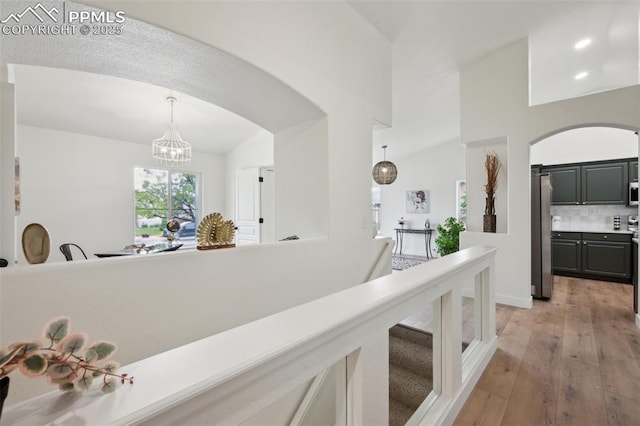 4530 Star Ridge Dr, Colorado Springs, CO 80916 - corridor featuring arched walkways, a chandelier, light wood-style flooring, and a towering ceiling
