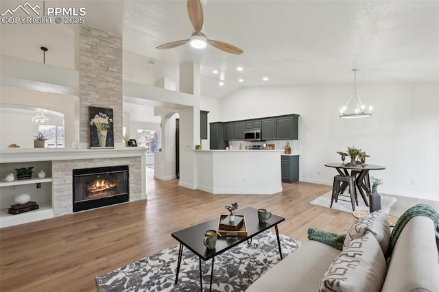 4530 Star Ridge Dr, Colorado Springs, CO 80916 - living area featuring ceiling fan, light wood-type flooring, a large fireplace, arched walkways, and baseboards