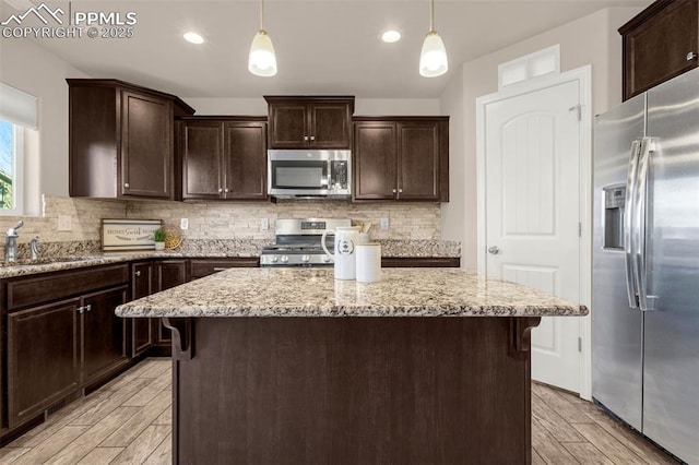 10881 Traders Pkwy, Fountain, CO 80817 - kitchen with appliances with stainless steel finishes, light wood finished floors, a sink, dark brown cabinets, and recessed lighting