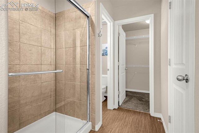 10881 Traders Pkwy, Fountain, CO 80817 - bathroom featuring wood finished floors, toilet, a stall shower, and a walk in closet