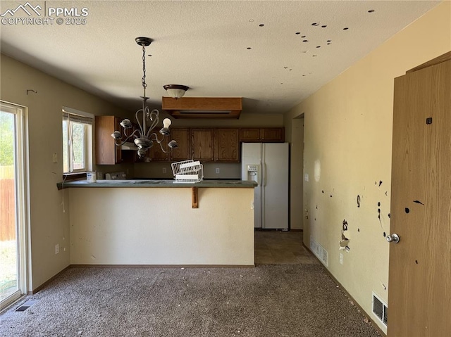 851 Legend Oak Dr, Fountain, CO 80817 - kitchen featuring white refrigerator with ice dispenser, dark countertops, a chandelier, a peninsula, and carpet