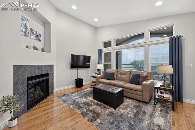 9661 Fresh Air Dr, Colorado Springs, CO 80924 - living area with wood finished floors, a tiled fireplace, baseboards, and recessed lighting