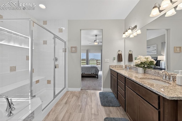 9661 Fresh Air Dr, Colorado Springs, CO 80924 - ensuite bathroom featuring double vanity, a shower stall, a ceiling fan, baseboards, and wood finished floors