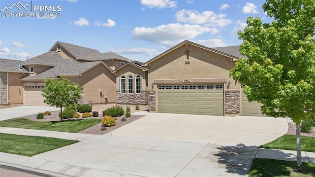 9661 Fresh Air Dr, Colorado Springs, CO 80924 - view of front of home featuring stucco siding, an attached garage, stone siding, and driveway