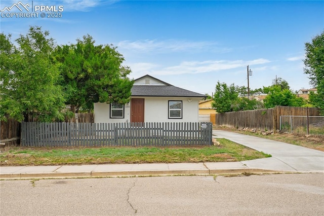 1205 Catalpa St, Pueblo, CO 81001 - view of front of property with stucco siding, a fenced front yard, and roof with shingles